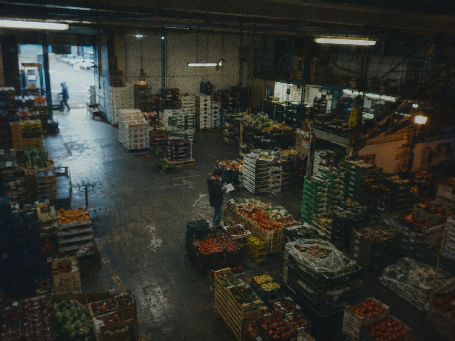 A market floor stacked with crates under strip light